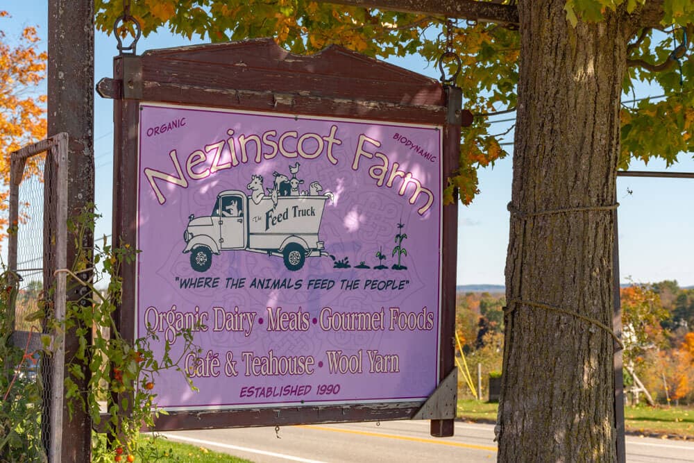 Sign for Nezinscot Farm featuring offerings like organic dairy, gourmet foods, and a café, established in 1990.