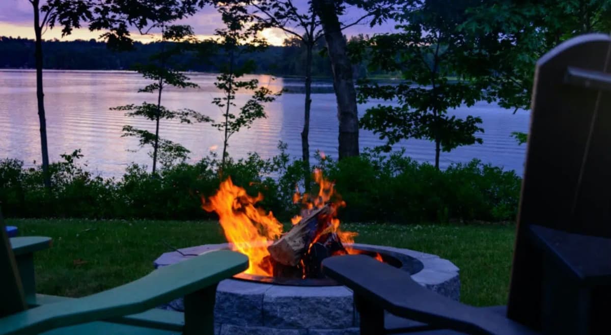 Cozy fire in the fire pit by Tripp Lake after sunset outside Wolf Cove Inn