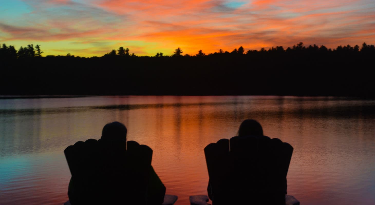 Silhouette of couple watching sunset together across lake
