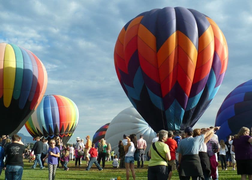 crowd of people gathered around colorful hot air balloons at a festival crowd of people gathered around colorful hot air balloons at a festival