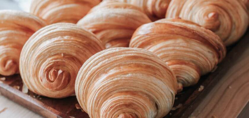 tray of freshly baked croissants with golden, flaky layers on a wooden surface