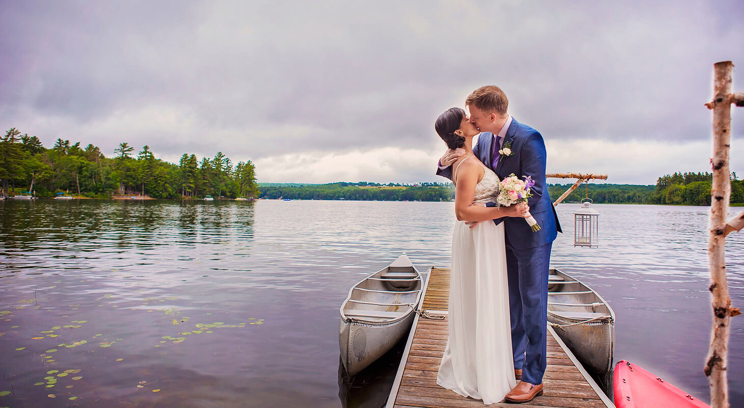 Newlywed couple kissing on a small dock