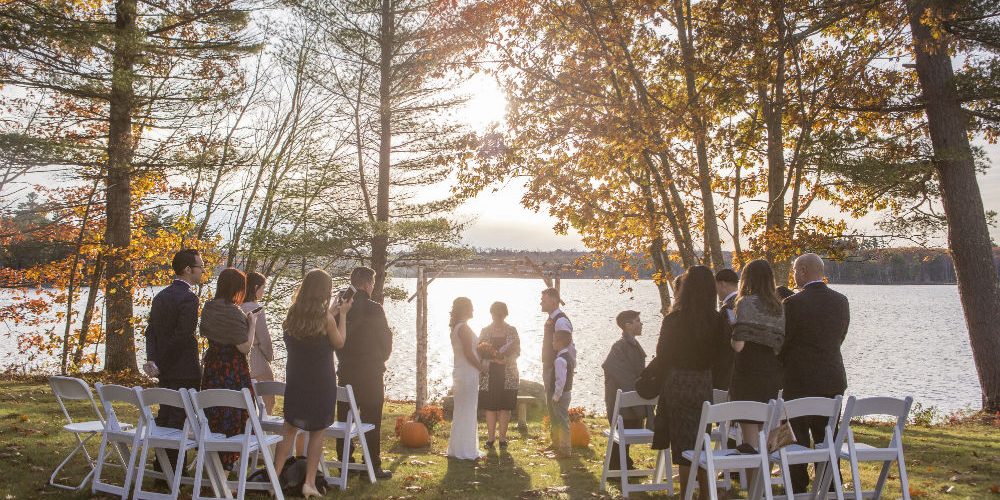 Small wedding party standing at wedding at sunset in a copse of fall trees