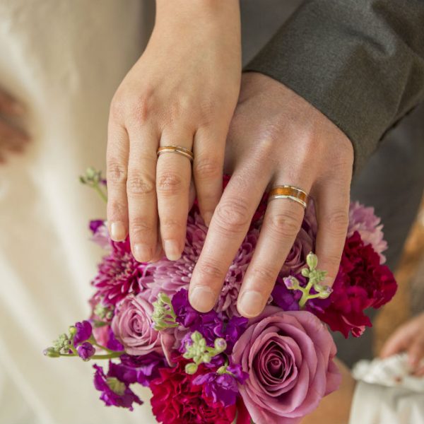 Bride's and groom's hands resting on bouquet