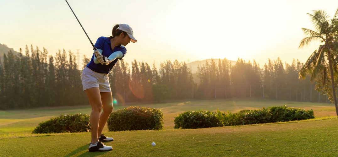 Young golfer winds up to swing her club in the morning