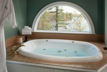 Shot of the filled warm bath tub and bathrobe next to the window overlooking Tripp Lake