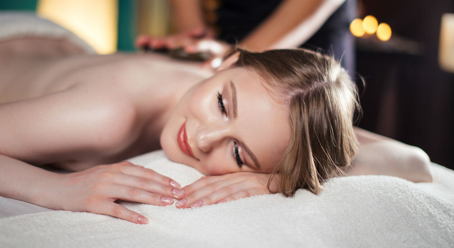 Young woman receives massage while lying on towel