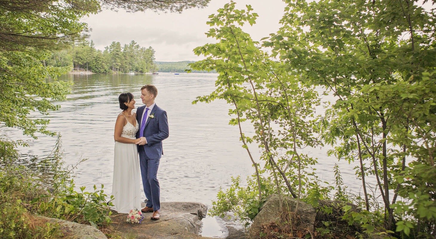 Bride and groom embrace in a grove by the lake