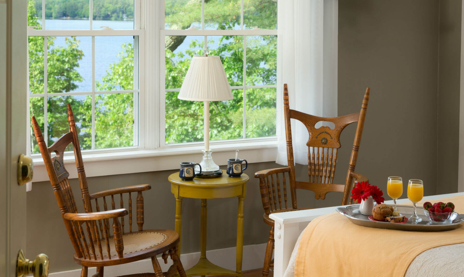 Sitting area with coffee under lamp by window overlooking lake