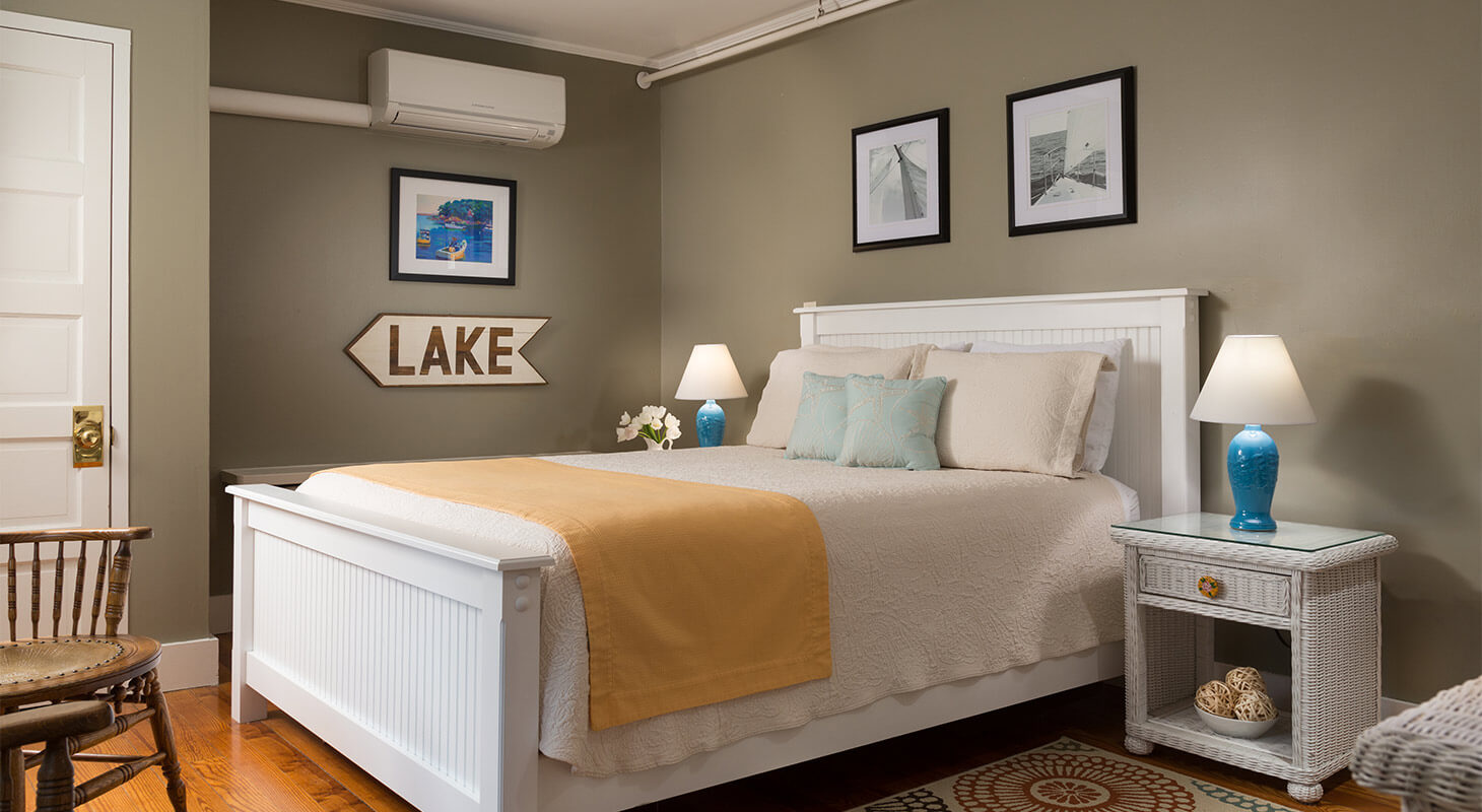 Comfortable bed next to lake sign and floral rug
