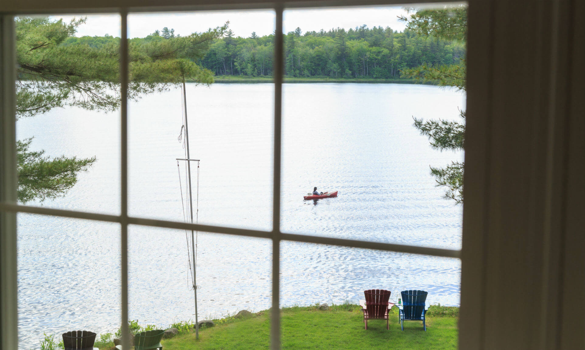 Window overlook into lake with canoer floating across it