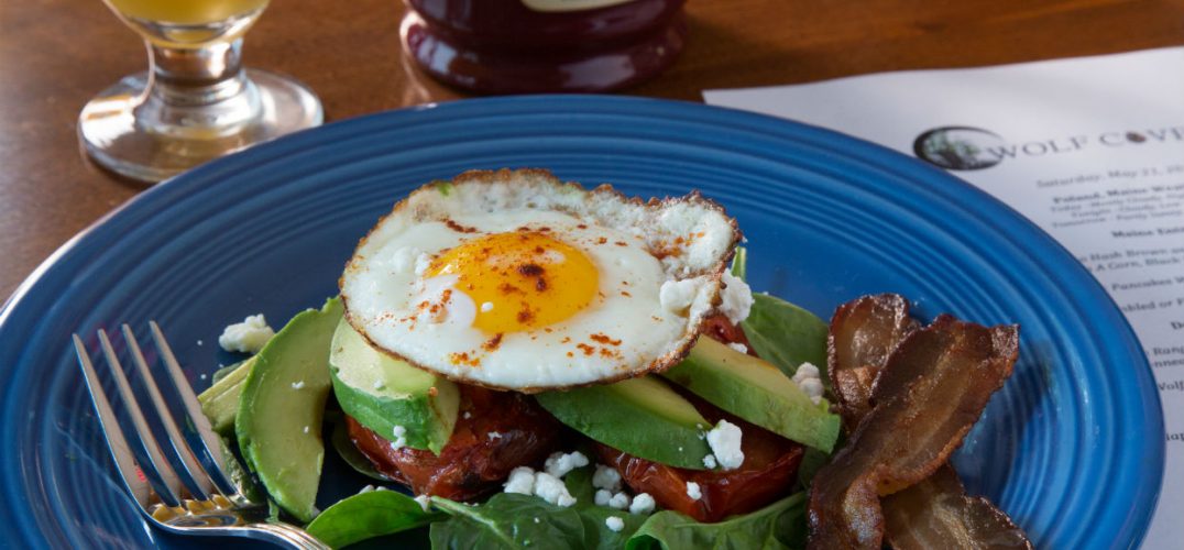 Fresh breakfast with fried egg, bacon, and avocado
