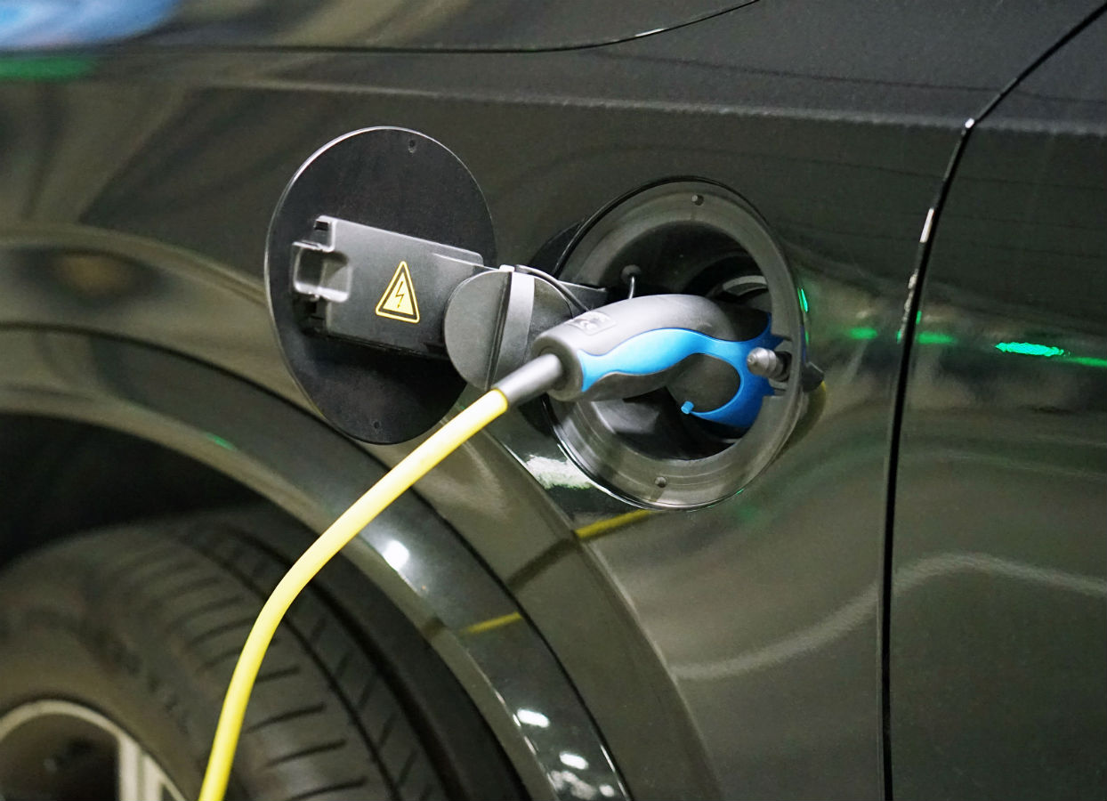 Black electric vehicle getting a recharge with a black and blue charge with a yellow cord