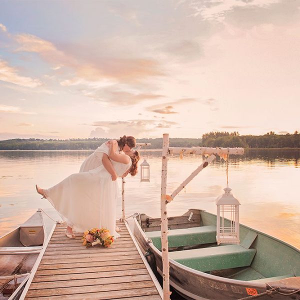 Brides kissing on dock at sunset
