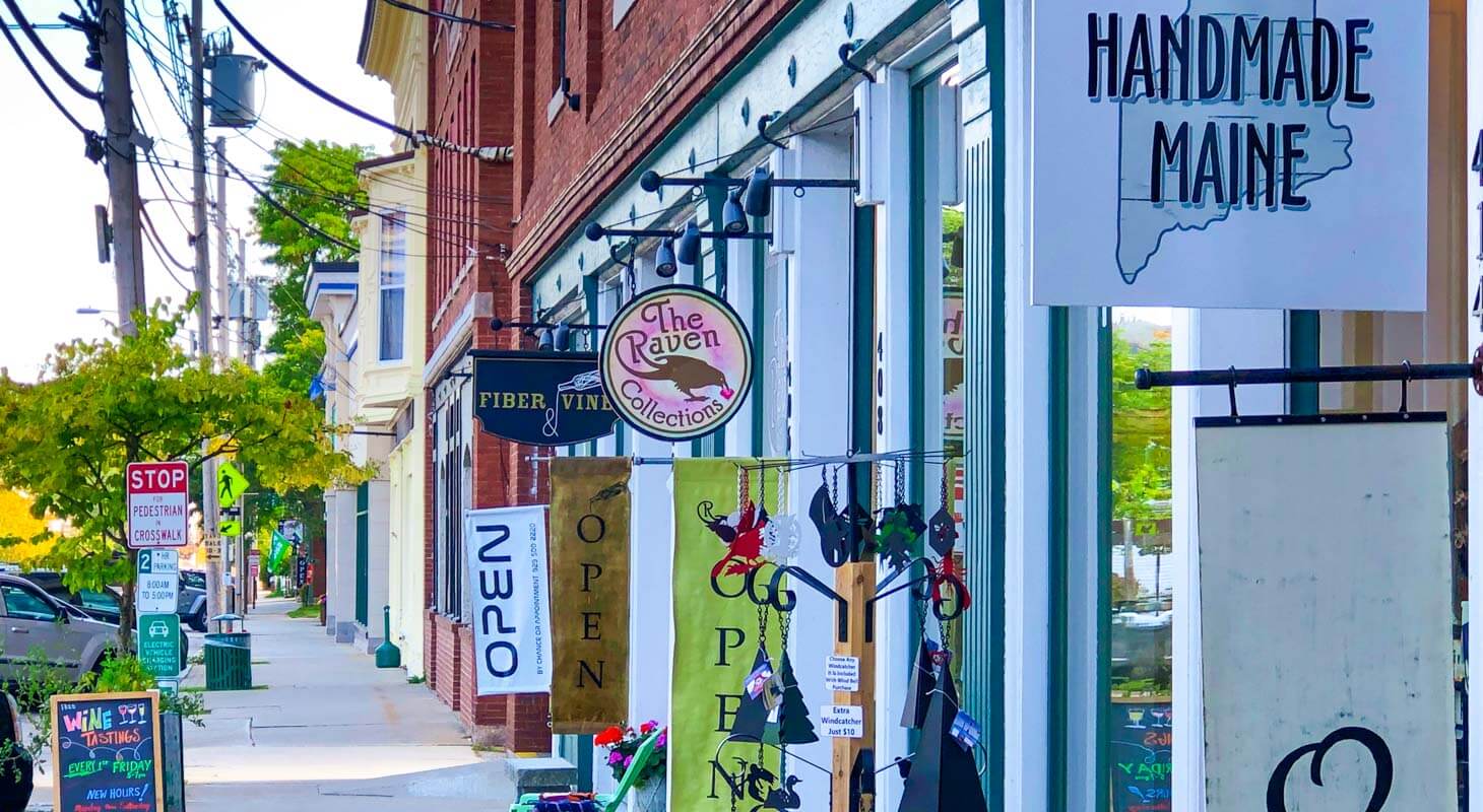 Open signs hang from shopping facades on Main St in Maine