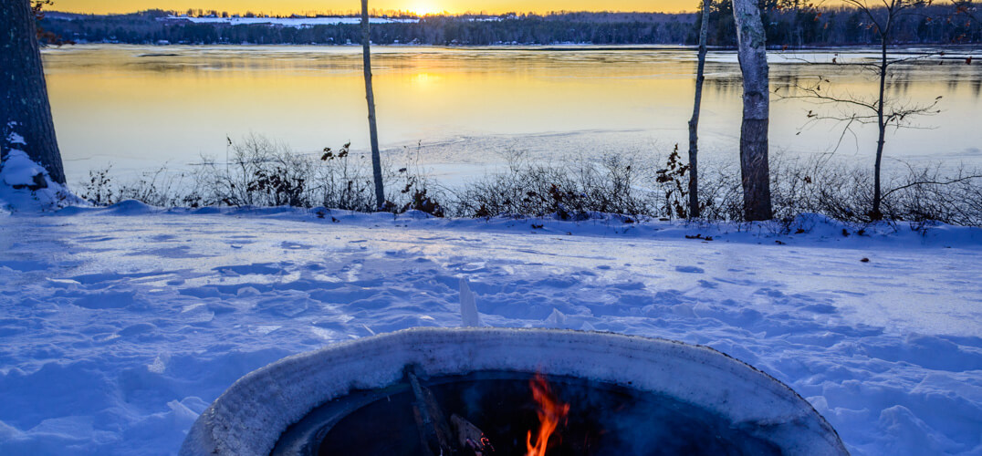 Firepit in winter overlooking frozen lake