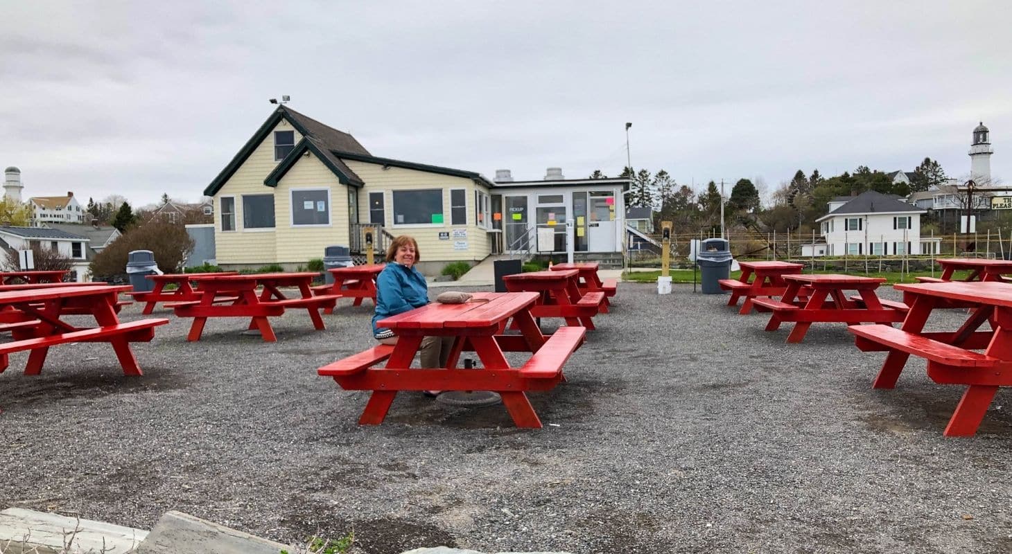 Sue sitting at a red picnic table at the Lobster Shack at two lights
