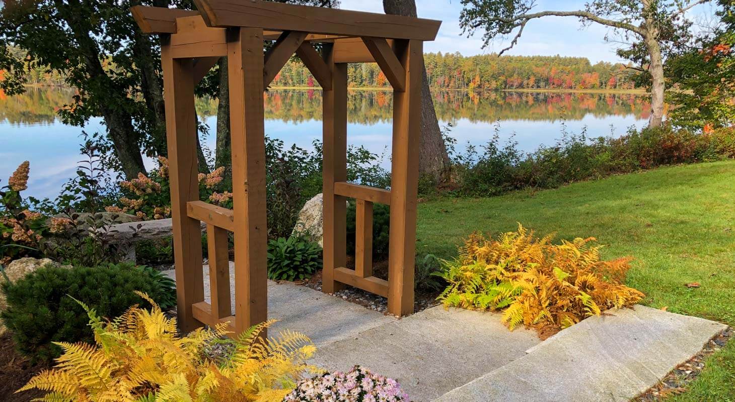 Outdoor wooden wedding arbor with a lake reflecting fall foliage in the background