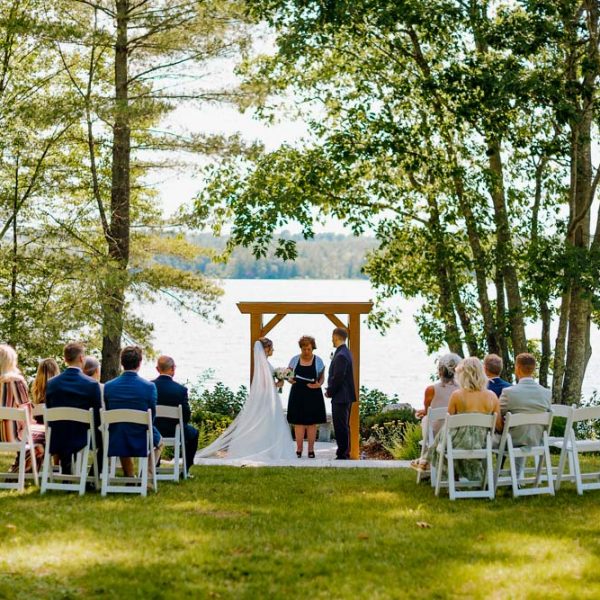 Couple getting married outdoors by a lake with ten guests
