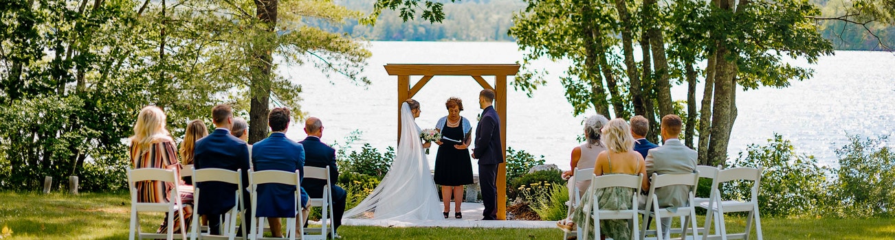 Couple getting married outdoors by a lake with ten guests