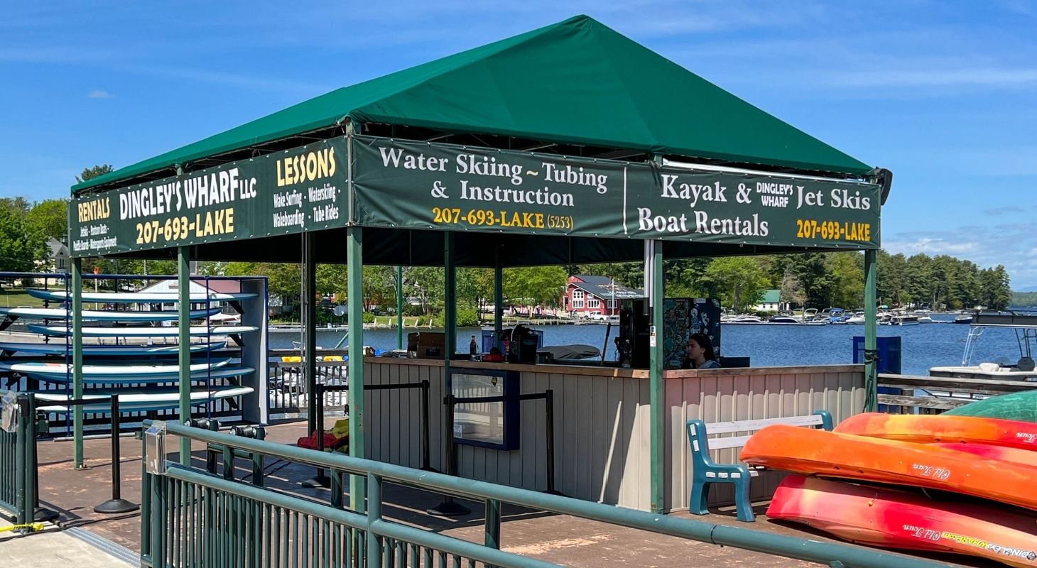 Green tent-like pavilion with signs for Dingley's Wharf offering boat rentals and lessons