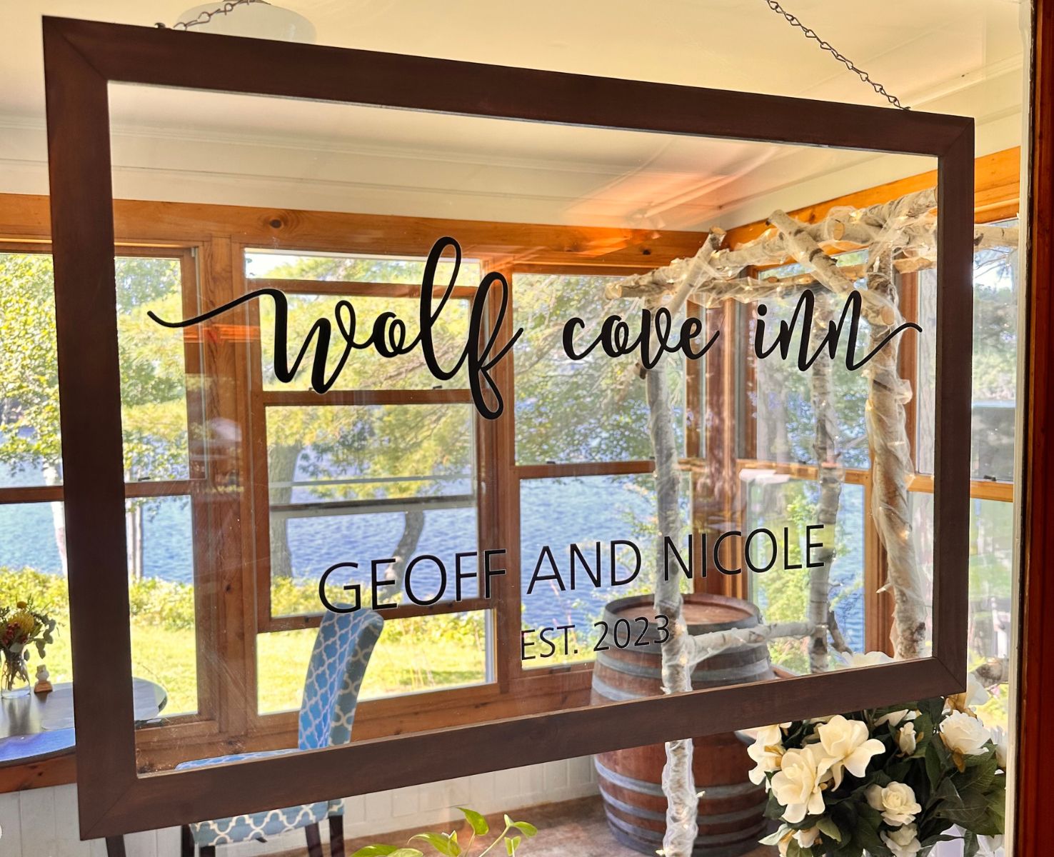 Wood framed glass sign etched with "Wolf Cove Inn, Geoff & Nicole Est. 2023"