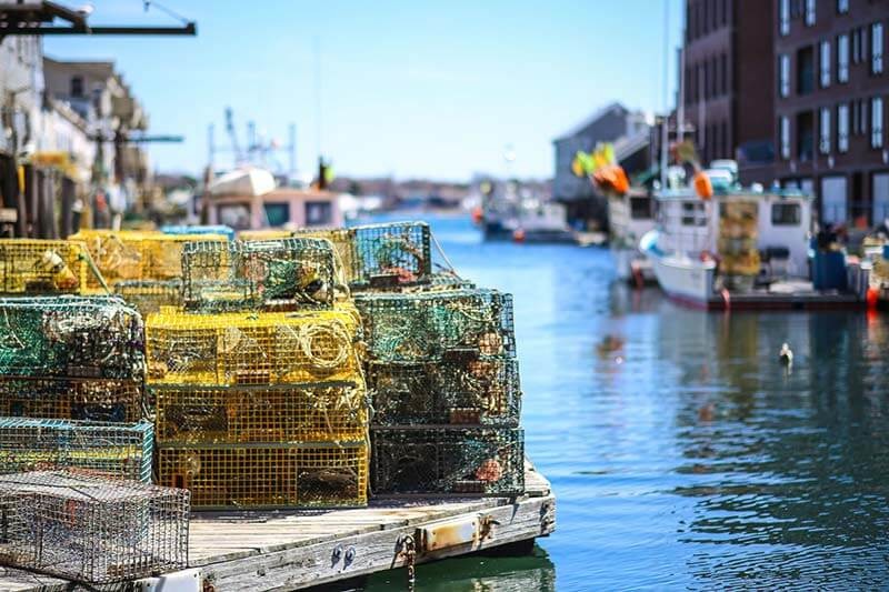 Lobster traps on a dock and fishing boats in Portland Maine